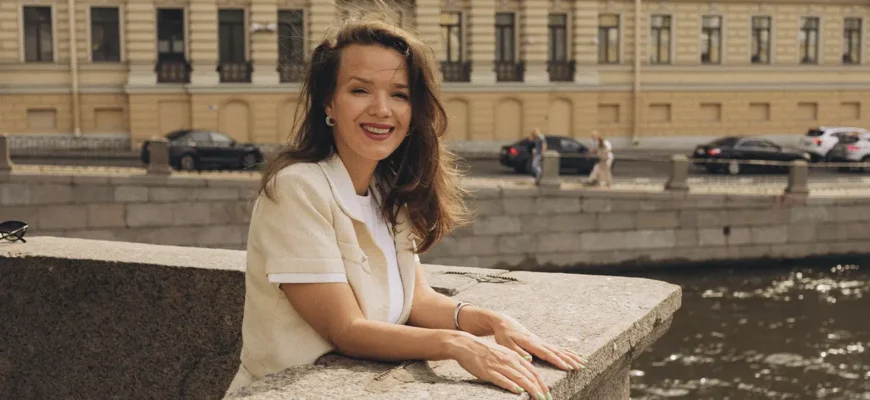 Психолог Татьяна Ивлева улыбается, опираясь на набережную в Санкт-Петербурге.